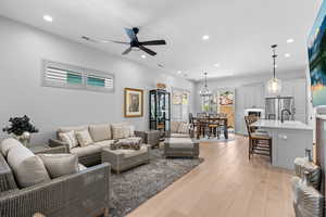 Living room with light wood-type flooring, a ceiling fan, a chandelier, and recessed lighting