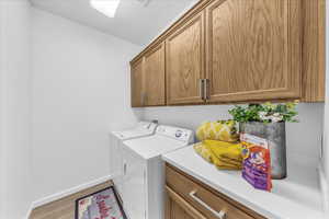 Laundry room with cabinet space, washing machine and clothes dryer, and light wood-type flooring