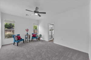 Living area with carpet floors and ceiling fan