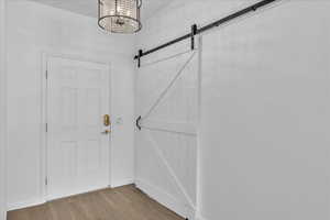 Doorway to outside featuring a chandelier, a barn door, and wood finished floors