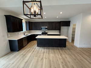 Kitchen with backsplash, a chandelier, a kitchen island, stainless steel appliances, and recessed lighting