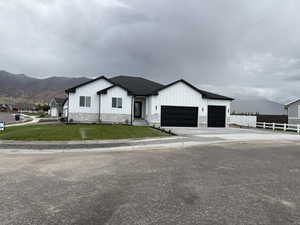 Modern farmhouse style home with board and batten siding, stone siding, driveway, an attached garage, and a mountain view