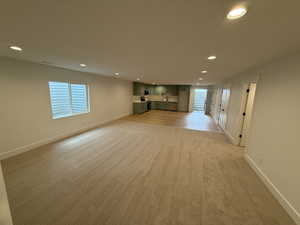 Unfurnished living room featuring light carpet, recessed lighting, and healthy amount of natural light