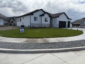 View of front of house with board and batten siding, a front lawn, driveway, stone siding, and an attached garage