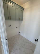 Washroom with electric dryer hookup, cabinet space, and washer hookup