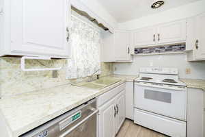 Kitchen featuring white range with electric stovetop, decorative backsplash, white cabinets, stainless steel dishwasher, and light countertops