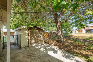 Fenced backyard with a shed and a patio area