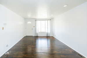 Unfurnished living room featuring dark wood-style floors, a textured ceiling, and recessed lighting