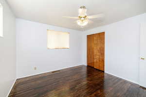 Unfurnished bedroom featuring dark wood-style floors, ceiling fan, and a closet