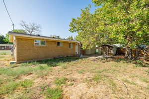 Rear view of property featuring a storage unit, brick siding, and a patio