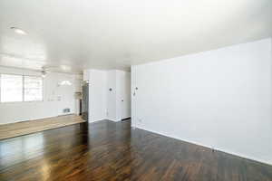 Unfurnished living room with dark wood-type flooring, a textured ceiling, and a ceiling fan