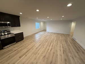 Kitchen with stainless steel appliances, recessed lighting, light countertops, light wood-type flooring, and open floor plan
