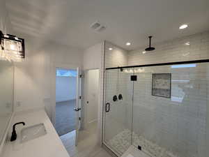 Bathroom featuring a shower stall, light tile patterned floors, vanity, and recessed lighting