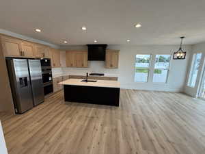 Kitchen featuring a kitchen island with sink, stainless steel appliances, recessed lighting, backsplash, and hanging light fixtures