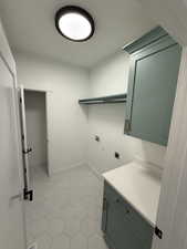 Laundry area with electric dryer hookup, washer hookup, cabinet space, and light tile patterned flooring