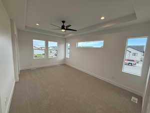 Unfurnished room featuring a raised ceiling, carpet floors, plenty of natural light, and recessed lighting