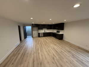 Kitchen with light countertops, recessed lighting, appliances with stainless steel finishes, light wood-type flooring, and dark cabinetry