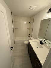 Bathroom featuring bathtub / shower combination, a textured ceiling, and vanity