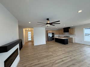 Kitchen with open floor plan, a center island with sink, light countertops, light wood finished floors, and recessed lighting