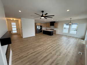 Kitchen featuring open floor plan, plenty of natural light, a center island with sink, light wood finished floors, and recessed lighting