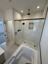 Bathroom with a stall shower, a bath, recessed lighting, and vanity