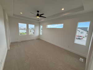 Unfurnished room with a raised ceiling, carpet, healthy amount of natural light, and recessed lighting
