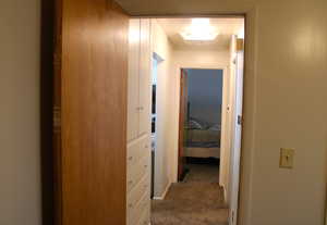 Corridor featuring dark colored carpet and baseboards