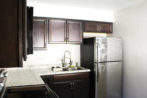 Kitchen featuring dark brown cabinets, freestanding refrigerator, light countertops, and electric range oven