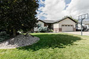 Single story home with a front yard, brick siding, a garage, stucco siding, and driveway