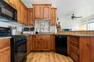 Kitchen featuring black appliances, brown cabinets, light stone countertops, light wood finished floors, and ceiling fan