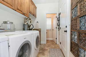 Laundry room featuring separate washer and dryer, cabinet space, and light tile patterned flooring leading to garage with a 1\2 bath