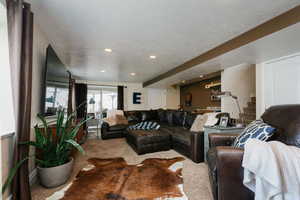 Carpeted living area with stairs, a textured ceiling, and recessed lighting with sliding glass door leading to outside area