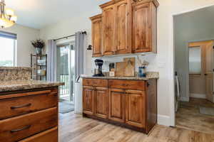 Kitchen featuring light stone counters, brown cabinetry, light wood-style floors, washer / dryer, and a chandelier