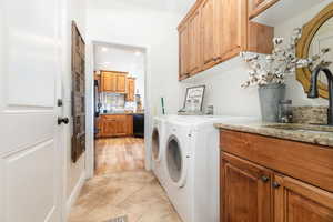 Washroom featuring cabinet space, independent washer and dryer, recessed lighting, and light tile patterned floorsright off of kitchen with door leading to garage