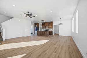 Unfurnished living room featuring light wood-type flooring, stairs, a ceiling fan, and recessed lighting