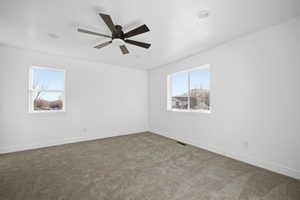 Empty room with plenty of natural light, carpet, and a ceiling fan