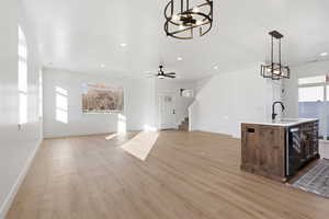 Unfurnished living room featuring a chandelier, light wood-type flooring, stairs, ceiling fan, and recessed lighting