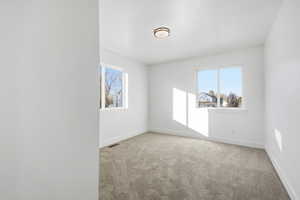 Unfurnished room with healthy amount of natural light and light colored carpet