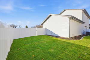 View of side of home featuring a fenced backyard and a gate