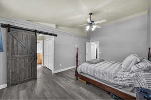 Bedroom featuring lofted ceiling, wood finished floors, a ceiling fan, ensuite bath, and a closet