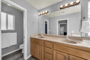 Full bathroom with double vanity and dark wood finished floors