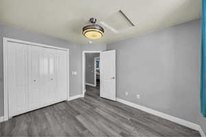 Unfurnished bedroom with attic access, light wood-style floors, and a closet