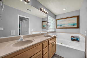 Full bath featuring double vanity, a jetted tub, and recessed lighting