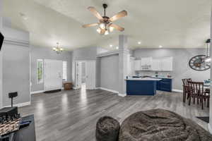 Living area featuring a chandelier, light wood-type flooring, lofted ceiling, a ceiling fan, and recessed lighting