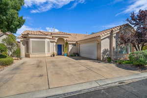 Mediterranean / spanish-style house with stucco siding, a tiled roof, a garage, and driveway