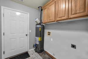 Laundry room featuring light tile patterned floors, hookup for a washing machine, water heater, cabinet space, and a textured ceiling