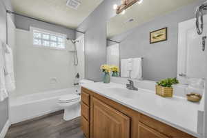Bathroom featuring tub / shower combination, vanity, and dark wood-style floors