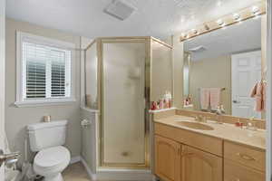 Full bathroom with vanity, a shower stall, a textured ceiling, and light tile patterned flooring