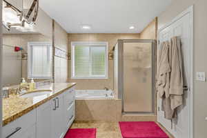 Bathroom with a stall shower, vanity, plenty of natural light, light tile patterned floors, and tile walls