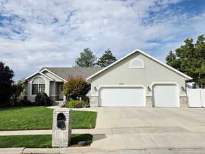 Ranch-style house featuring concrete driveway, stucco siding, a front yard, and an attached garage